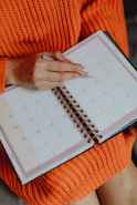 person holding white book planner